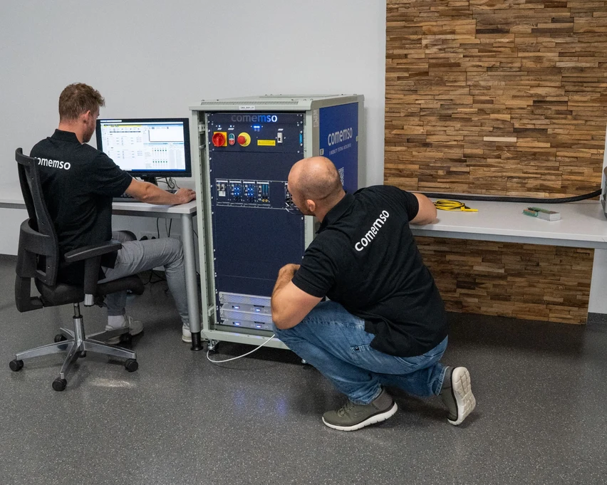 Two comemso employees working with a Battery Cell Simulator and its control software.