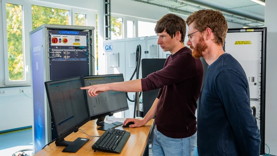 Two comemso employees working with an EVSE test setup in the laboratory.