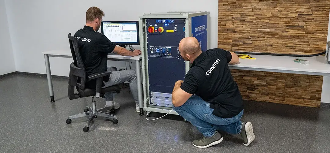 Two comemso engineers working on a test rack in the lab