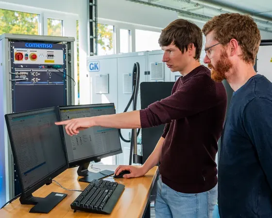 Two comemso employees working with an EVSE test setup in the laboratory.